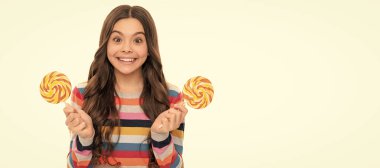 Beyaz arka planda izole edilmiş lolipop şekerli renkli süveter giyen şaşkın çocuk, tatlı bir hayat.