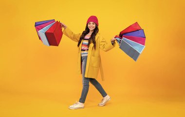 Stylish teen girl with shopping sale bags. Kid holding purchases. Happy teenager, positive and smiling emotions of teen girl