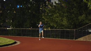 Akşamları yarış pistinde koşan bir adam. Koşucu inanılmaz bir hızla koştu. Spor koşucusu maratonu tamamlıyor. Spor eğitimi. Sporcu adam antrenman için koşuyor. Spor rutini.