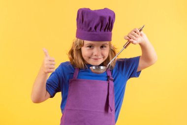 Mutfak kepçesiyle aşçı çocuk, stüdyo portresi. Yemek pişirme, aşçılık ve çocuklar. Stüdyoda izole edilmiş şapka ve önlüklü küçük çocuk.