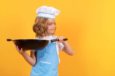 Tavalı küçük bir aşçı. Şef çocuk sağlıklı yemek hazırlıyor. Şef şapkalı bir çocuğun stüdyo portresi.