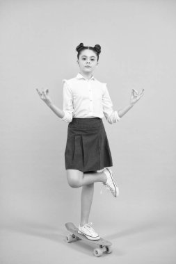 Teen girl 12, 13, 14 years old with skateboard over studio background. Cool modern teenager in stylish clothes. Teenagers lifestyle, casual youth culture