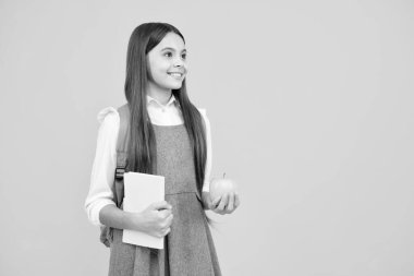 Okula dönelim. Okul çocuğu, çantalı genç kız. Elma ve kitap sarıda izole edilmiş.