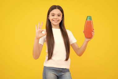 Şampuan kremi kullanan bir çocuk. Günlük kozmetik bakım. Gençlerin elinde saç ve cilt bakımı şişesi var. Güzellik sağlığı ve kozmetik ürünleri. Mutlu ergen portresi. Gülümseyen kız