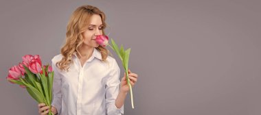 cheerful blonde woman with spring tulip flowers on grey background. Woman isolated face portrait, banner with mock up copy space