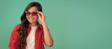 Genç bir kızın güzel görünüşü. Mavi arka planda çocuk portresi. Çocuk yüzü, yatay poster, izole edilmiş genç kız portresi, fotokopi alanı olan pankart