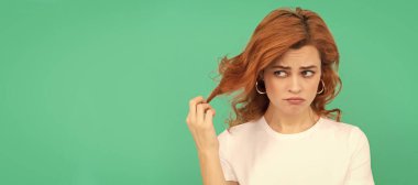 Mavi arka planda kıvırcık saçlı mutsuz kızıl kadın, hayal kırıklığı. İzole edilmiş yüz portresi, kopyalama alanı olan pankart