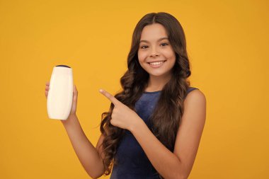 Teenage girl with shampoos conditioners or shower gel. Kids hair care cosmetic product, shampoo bottle. Happy girl face, positive and smiling emotions