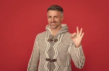 Mutlu yakışıklı adam kırmızı arka planda süveter giyer..