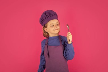 Child cook hold spoon. Cooking children. Chef kid boy making healthy food. Portrait of little child in chef hat isolated on studio background. Kid chef. Cooking process