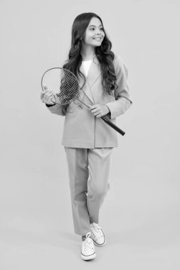 Teen girl badminton player in suit with badminton racket isolated on yellow background