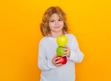 Apples. Kid with apple in studio. Studio portrait of cute child hold apple isolated on yellow background