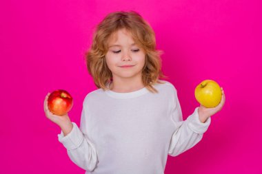 Stüdyoda elmalı çocuk. Stüdyo portresi pembe arka planda izole edilmiş elma tutan şirin çocuk.