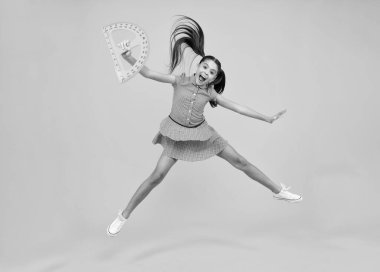 Şaşırmış bir genç. Okul ekipmanlarını ölçüyorum. Okul kızı geometri dersi için ölçü tutuyor, sarı arka planda izole edilmiş. Çılgın atlayış, zıplayan çocuklar. Öğrenci matematiği okuyor. Heyecanlı genç kız