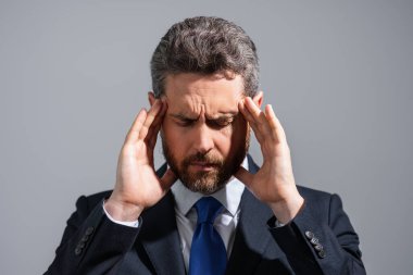 Takım elbiseli stresli iş adamının başı ağrıyor. Yorgun iş adamı fazla mesai yapıyor ve başı ağrıyor. Çok çalışan adam baş ağrısından muzdariptir. Aşırı çalışma, teslim tarihi, iş yerinde zor migren.