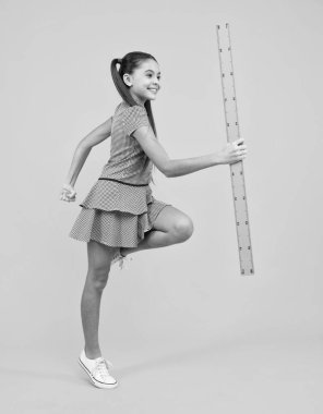 Okul kızı geometri dersi için ölçü tutuyor, sarı arka planda izole edilmiş. Ölçüm aletleri. Öğrenci matematiği okuyor. Mutlu ergen, pozitif ve gülümseyen liseli kız duyguları