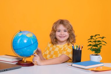 İlkokuldan coğrafya dersi sırasında dünyaya bakan bir çocuk. Küçük öğrenci, zeki inek öğrenci çalışmaya hazır. Okula ilk gelişim. Eğitim ve öğrenim kavramı