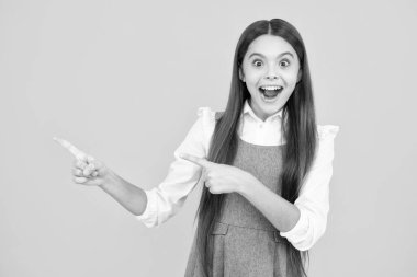 Heyecanlı bir yüz. Şaşırtıcı bir ifade, neşeli ve mutlu. Onun yakın plan portresi. Güzel, çekici, neşeli, şaşkın kız. Sarı arka planda izole edilmiş fotokopi alanını işaret ediyor.