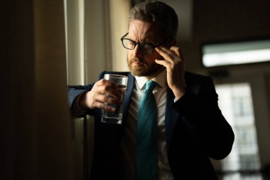 Ofiste başı ağrıyan stresli bir iş adamı. Yorgun iş adamı fazla mesai yapıyor ve başı ağrıyor. İş yerinde laptopla çok çalışan bir adam, baş ağrısı çekiyor. Aşırı çalışmaktan migrenim tuttu.