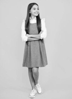 Okul üniforması. Güzel bir genç kızın tam boy fotoğrafı sarı arka planda izole edilmiş günlük kıyafetler giyiyor.