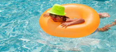 Child splashing in swimming pool. Active healthy lifestyle, swim water sport activity on summer vacation with child. Child in water play with inflatable toy ring