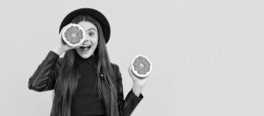 happy teen girl in hat and leather jacket hold cut grapefruit, healthy food. Child girl portrait with grapefruit orange, horizontal poster. Banner header with copy space