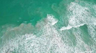 Okyanus kıyısında. Deniz kıyısına dalga geliyor. Su dalgasında muhteşem bir hava manzarası. Denizde dalgalar. Dalgalar dolusu su. Okyanus girdapları. Turkuaz suyu olan havadan kumsal. Su hareketi.