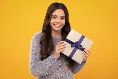 Yeni yıl ya da Noel hediyesi. Mutlu ergen, pozitif ve gülümseyen genç kız duyguları. Stüdyonun arka planında hediye kutusu olan çocuk. Çocukların doğum günü hediyesi.