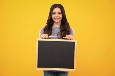 Okul satış kurulu. Neşeli genç kız, sarı arka planda fotokopi alanı olan karatahta tutuyor. Mutlu ergen, pozitif ve gülümseyen genç kız duyguları