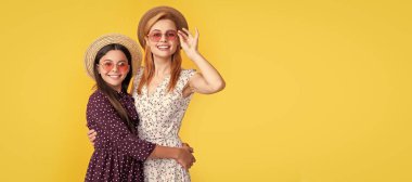 Mother and daughter kid banner, copy space, isolated background. mother and daughter smile in straw hat on yellow background