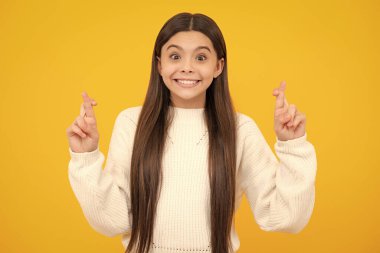 Şans dilemek için şans dileyen komik ergen çocuk. Kız dua eder ve hayallerin gerçekleşmesini umar, sarı arka planda izole edilmiş.