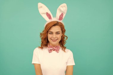 Tavşan kulaklı mutlu Paskalya kadını ve mavi arka planda papyon..