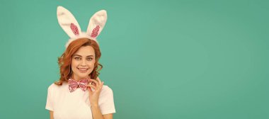 positive easter girl in bunny ears and bow tie on blue background. Woman isolated face portrait, banner with mock up copyspace