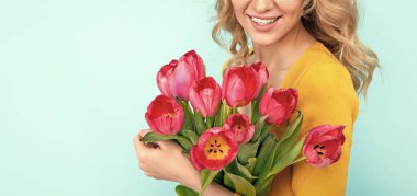 happy young woman with spring tulip flowers on blue background. womens day.