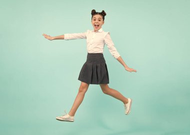 Mutlu zıplayan gençler. Mutlu liseli kız, pozitif ve gülümseyen genç kız duyguları. Mavi stüdyodaki genç kızın uzun atlayışı günlük etek ve gömlek giyer.