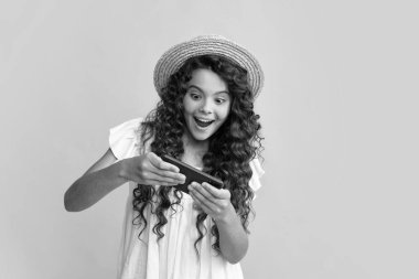 Akıllı telefonu olan ergen bir kız. Cep telefonu kullanan genç bir çocuğun portresi, cep telefonu uygulaması. Şaşırmış yüz, şaşırmış genç kız duyguları.