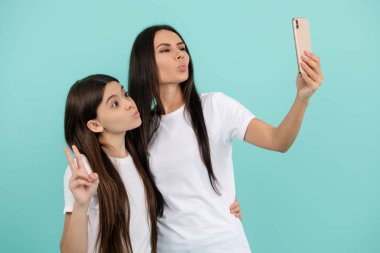 Anne ve kızıyla selfie. Anı yakala, anıya değer ver. Anne ve kızıyla birlikte portre. Anne ve kızı selfie çekiyor. Anne ve kızı selfie çekiyorlar.
