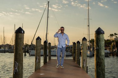 Lüks deniz seyahati, yaz tatili, özgürlük ve keyif teknesindeki seksi adam. Dışarıdaki mankenin portresi. Moda erkeği yatların yanında poz veriyor. Lüks yatın yanındaki yat limanında bir adam.