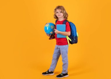 School boy with backpack globe and book. Little student on yellow isolated background. Learning, education and knowledge
