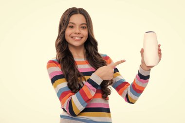 Child teen girl with shampoos conditioners and shower gel. Long hair care of teenager. Presenting cosmetic product, shampoo bottle. Happy girl face, positive and smiling emotions