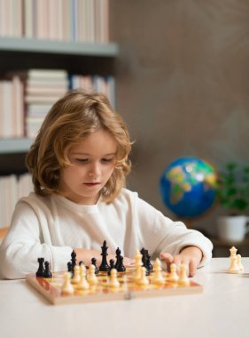 Akıllı konsantre ve düşünen çocuk satranç oynuyor.