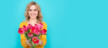 Mavi arka planda bahar lale çiçekleri olan neşeli bir kız. İzole edilmiş yüz portresi, taklit alanı olan pankart.