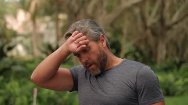 Sporcu koştuktan sonra kaslarını esnetiyor. Spor adamı antrenman için ısınıyor. Esneme hareketleri. Yorgun, olgun İspanyol koşucu rahatla. Açık havada spor yaptıktan sonra kasları ısıtıyorum..