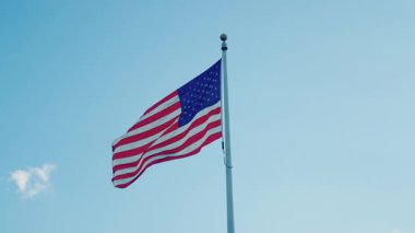 Amerikan Anma Günü ya da 4 Temmuz. Rüzgarda dalgalanan Amerikan bayrağı. ABD bayrağı. Ulusal bayrak sallayarak mavi gökyüzünde Birleşik Devletler. Bağımsızlık Günü. Vatanseverlik sembolü. Tarihsel bayrak dalgalanıyor.
