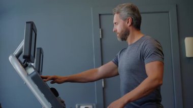 Koşu bandı çalışıyor. Sporcu spor salonunda koşu bandında koşuyor. Spor salonunda koşu bandı egzersizi. Kardiyo egzersizleri. Spor salonunda koşu bandında koşan atletik adam. Spor adamı spor eğlencesi..