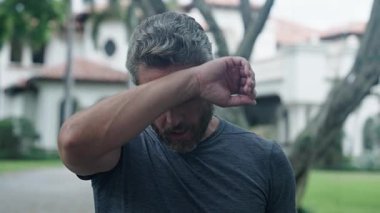 Sporcu adam rahatlamak için durur. Yorgun, olgun İspanyol koşucu rahatla. Terini sil. Dışarıda spor yaptıktan sonra terliyorum. Yetişkin adam koştuktan sonra zor nefes alıyor. Etkin yaşam biçimi.