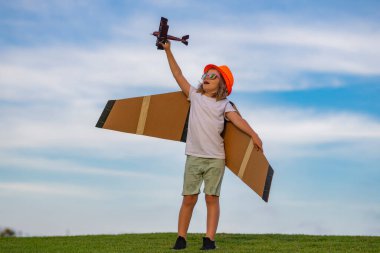 Kid having fun with toy airplane in field. Child pilot aviator with airplane dreams of traveling in summer in nature