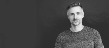 Man face portrait, banner with copy space. positive grizzled guy in sweater on red background,