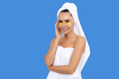 Göz bantlı bir kadın. Nemlendirici göz bantları olan güzel bir kadın. Yüz bakımı, kozmetoloji, altın göz bantları. Gözlerinde kozmetik bantları olan genç ve güzel bir kadın. Yüz derisi