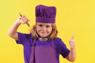 Mutfak kepçesiyle aşçı çocuk, stüdyo portresi. Aşçı üniformalı küçük bir çocuğun portresi. Şef çocuk stüdyo arka planında izole edilmiş. Aşçı olmak için sevimli bir çocuk. Aşçı şapkası giymiş bir çocuk.